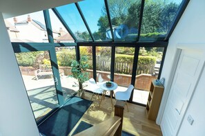 A modern room with large windows, a wooden bench, a small round table, and a white chair. - An outstanding, modern Annex with superb views- Pass the Keys (Stretton)