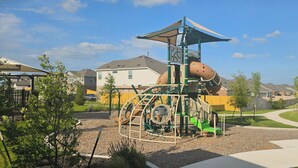 A playground with a climbing structure, a slide, and a swing set.