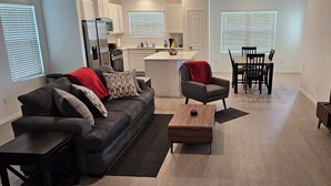 A modern living room with a sofa, coffee table, TV, and dining area.