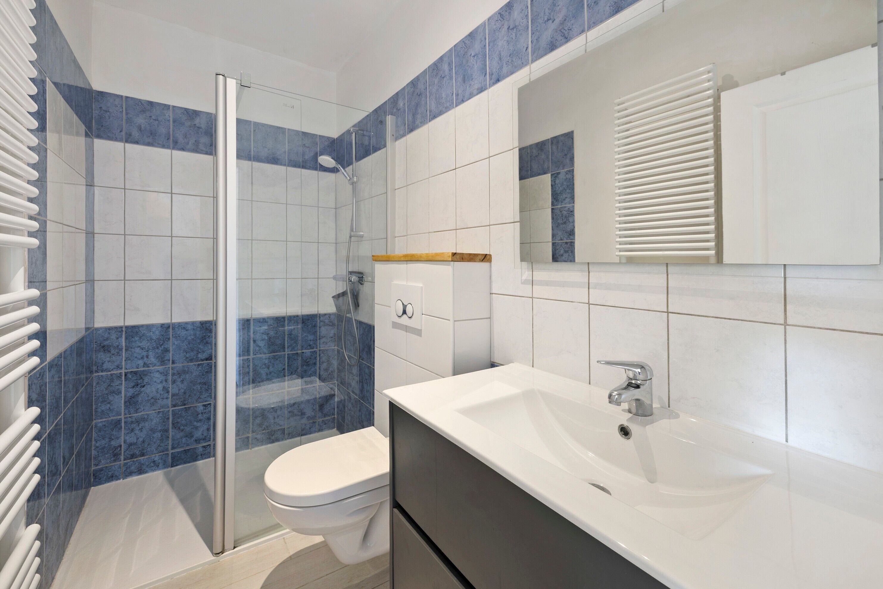 Un baño moderno con cabina de ducha de vidrio, inodoro blanco, lavamanos con espejo y un mueble.