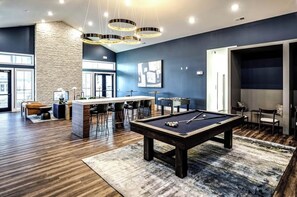 Una sala de estar moderna con mesa de billar, barra y asientos.
