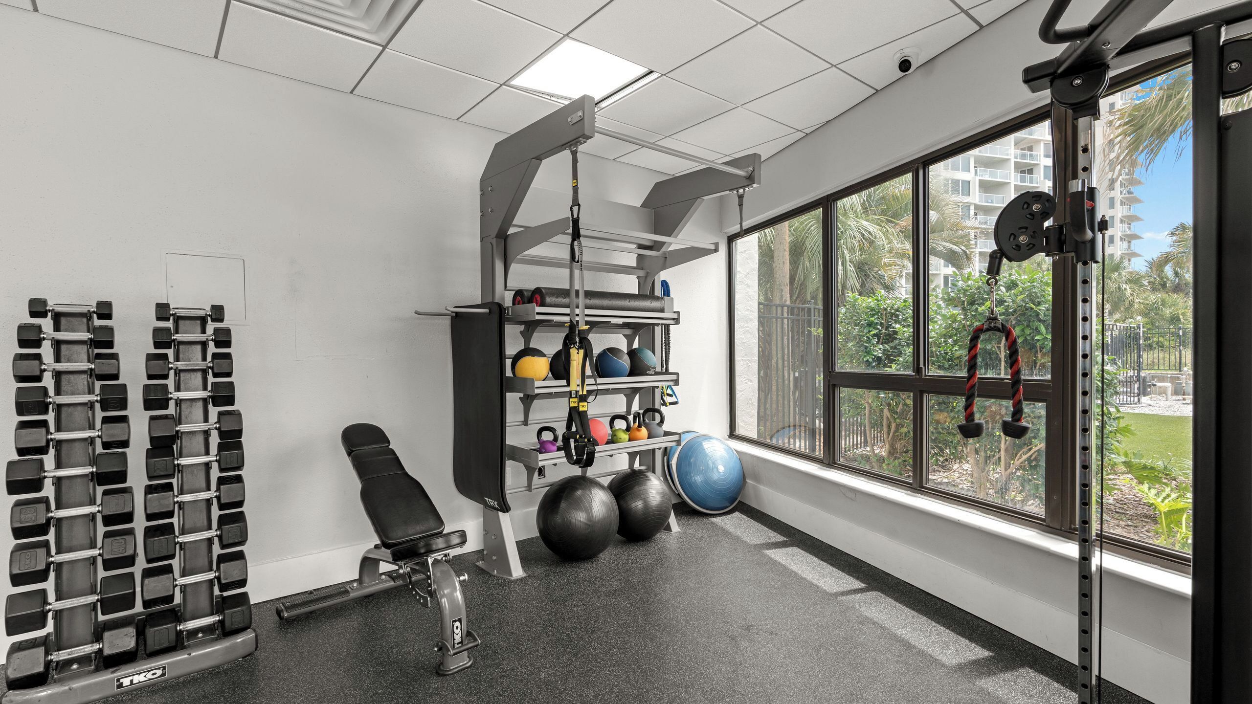 A gym with weight racks, exercise balls, and a bench.