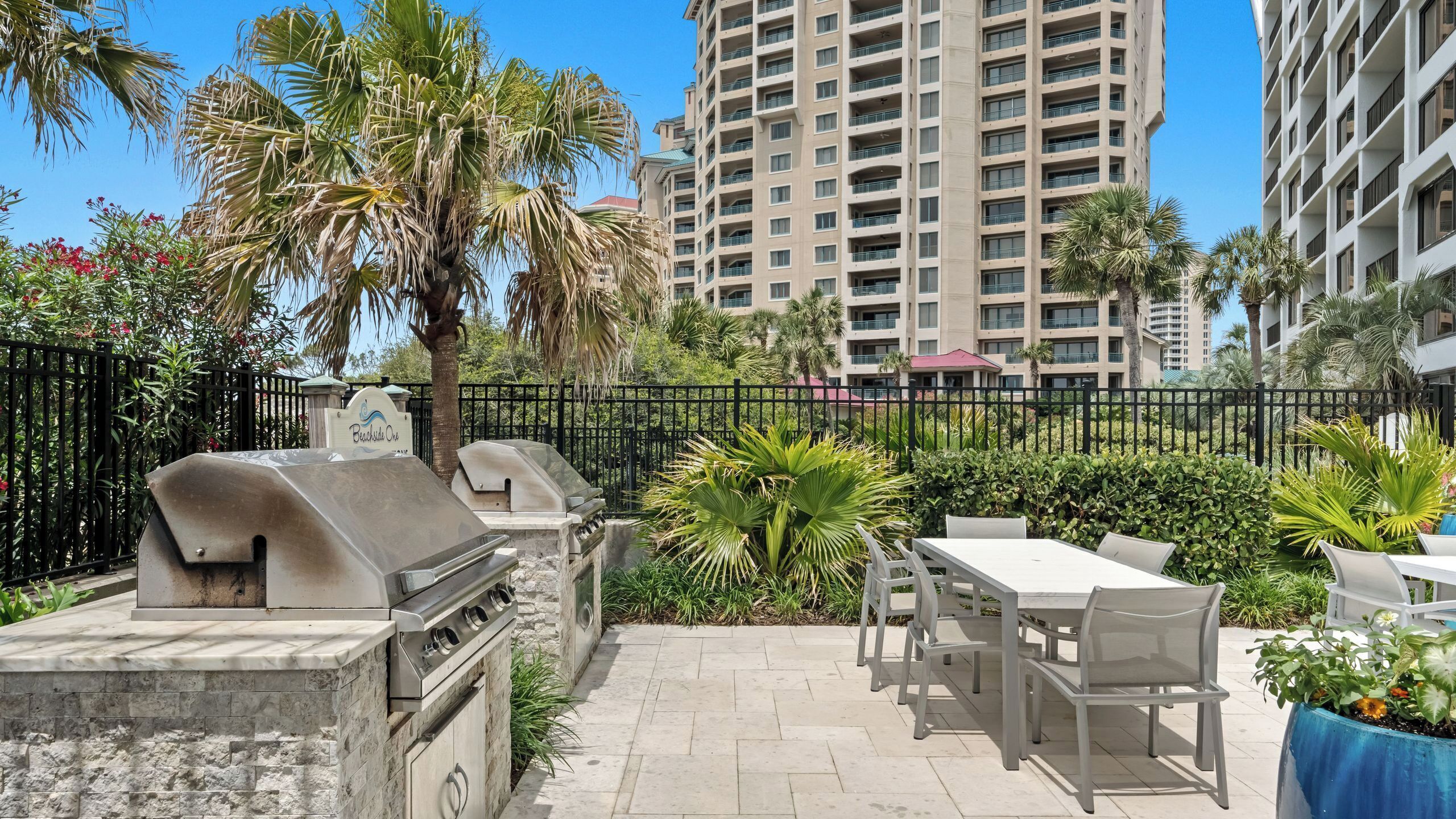 An outdoor patio area with a grill, seating, and a fence.