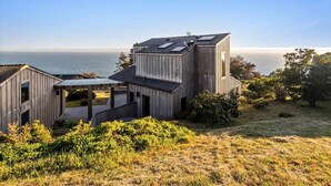 Ein modernes Holzhaus mit Meerblick, ausgestattet mit einer großen Terrasse und einem überdachten Außenbereich.