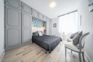 A bedroom with a bed, a chair, and a wardrobe. - La Perle du Port : Vue Panoramique et Terrasse (La Trinité-sur-Mer)