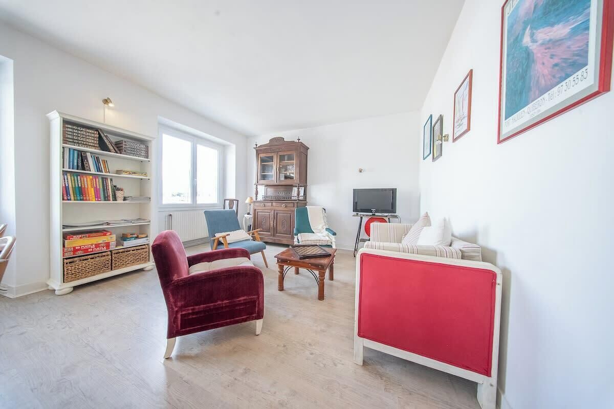 Een woonkamer met een boekenkast, een rode bank, een houten kast en een televisie.