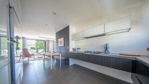 Cozinha moderna com uma ilha grande, armários escuros e vista para o exterior.