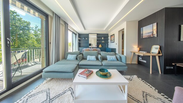 Uma sala de estar moderna com um sofá seccional, uma mesa de centro e vista para o exterior.