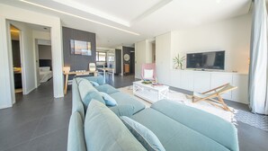 Uma sala de estar moderna com um sofá, uma mesa de centro, uma televisão e um espaço de jantar.