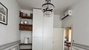 Een kamer met twee bedden, een kroonluchter, een garderobe, planken met boeken en vazen, en een airconditioning.