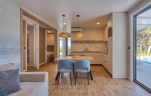 A modern kitchen with a marble countertop, a dining area with two chairs, and a large sliding glass door leading to a pool. - Luxurious home in Seget Vranjica with sauna (Seget Vranjica)