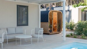 A modern outdoor seating area with a pool, a wooden sauna, and a covered patio. - Stunning home in Seget Vranjica with sauna (Seget Vranjica)