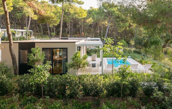Eine moderne Villa mit Pool, umgeben von dichtem Wald.