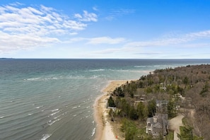 A coastal view with a beach, ocean, and residential area with houses and trees.