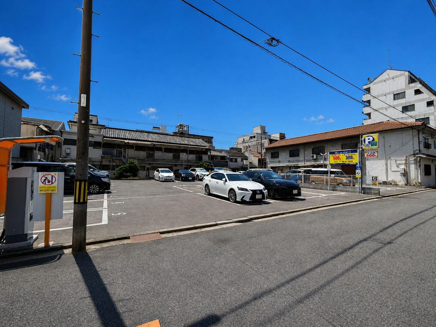 Un parcheggio con auto, un edificio con un cartello e un cielo azzurro limpido.