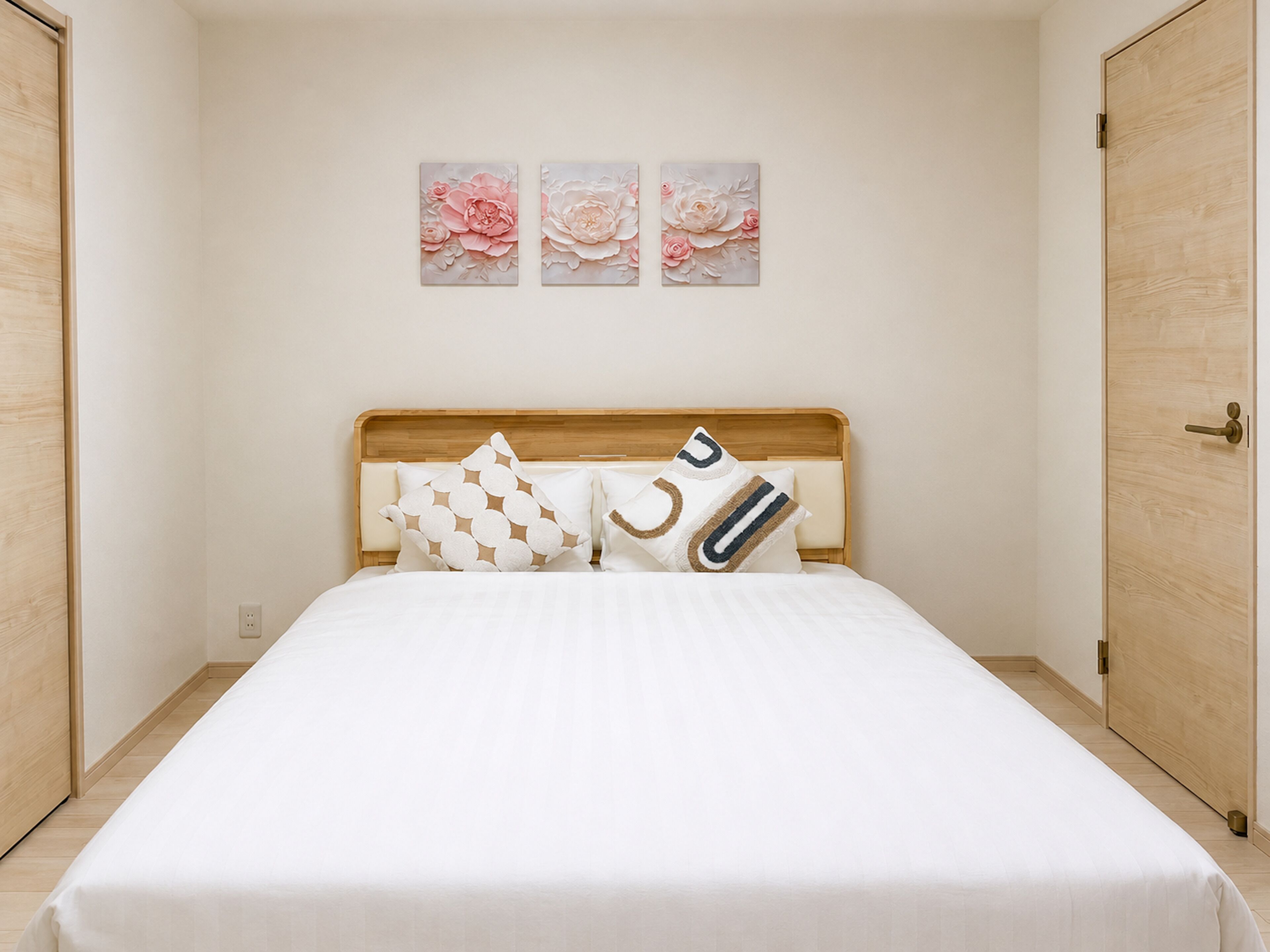 A bedroom with a wooden headboard, a bed with white bedding, and three floral wall art pieces.