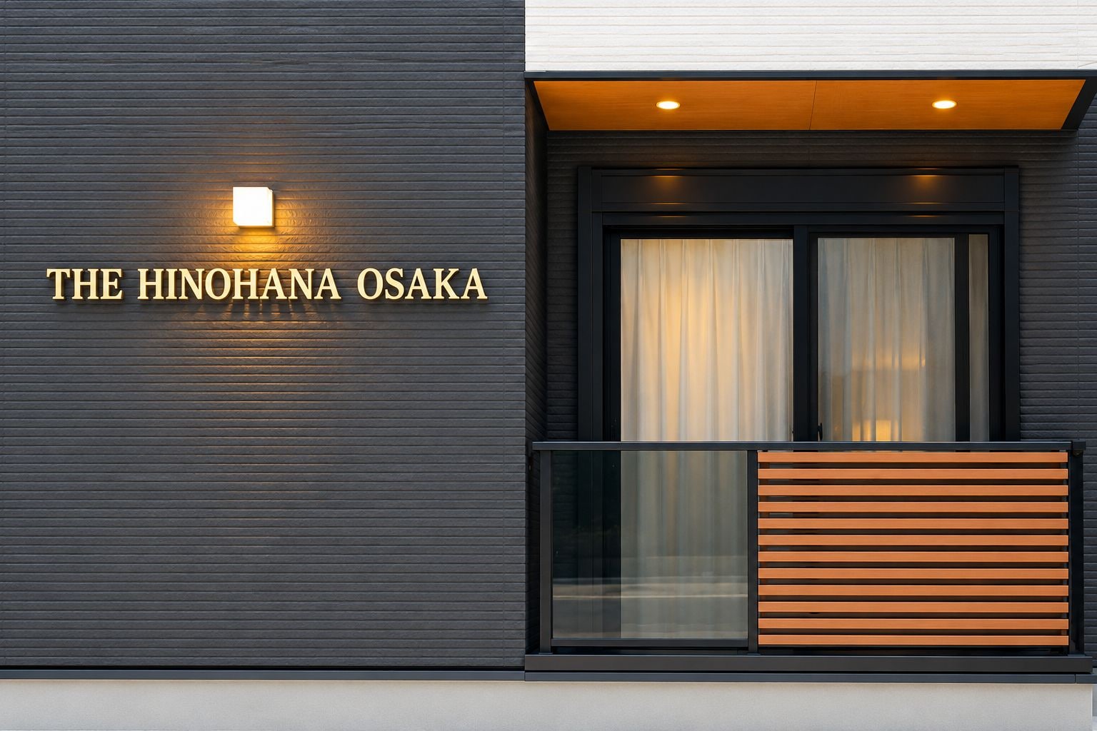 Une façade d’immeuble avec l’enseigne « THE HINOHANA OSAKA », une entrée moderne dotée d’une porte en verre et un balcon avec des lattes en bois.