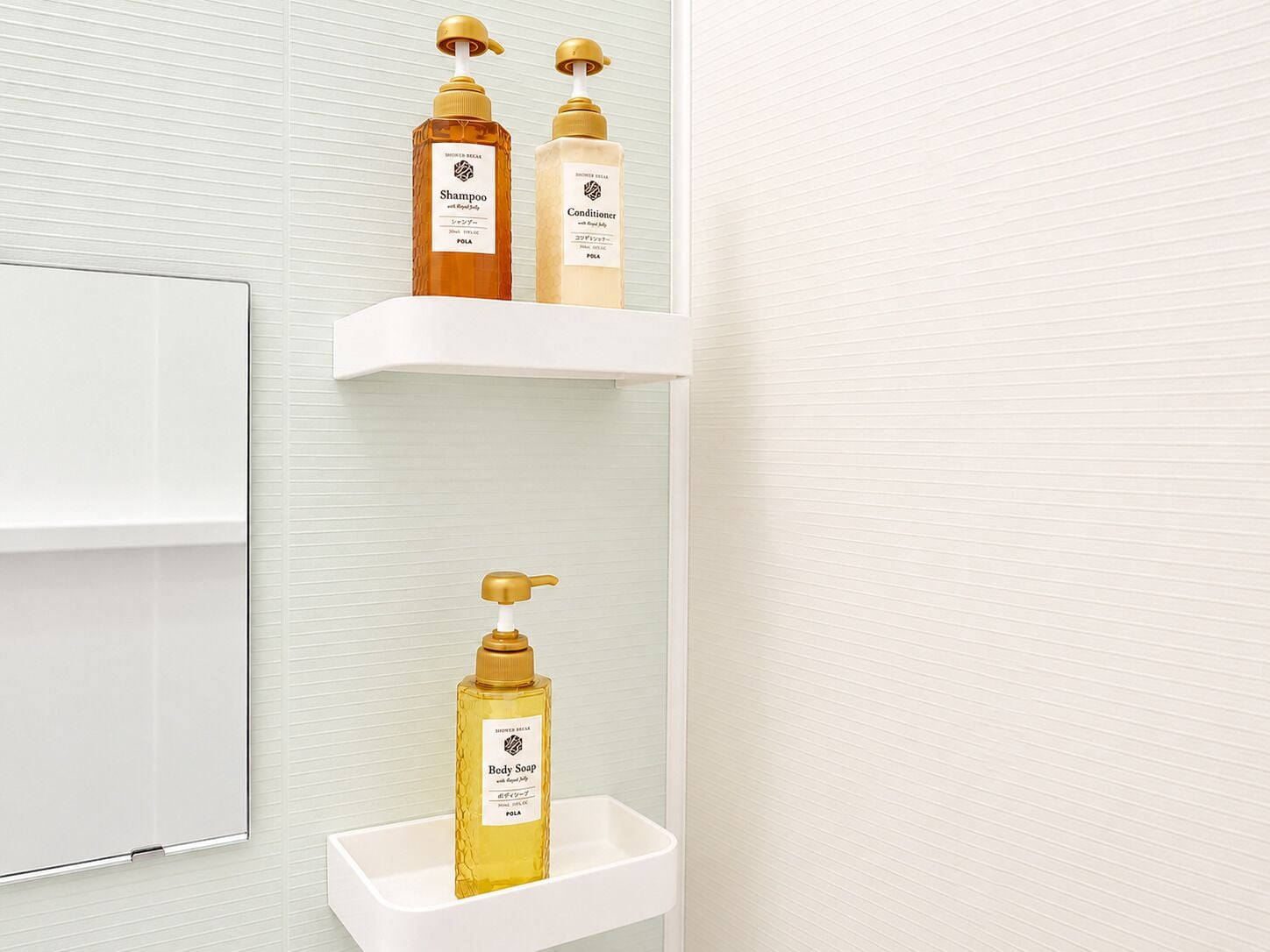 A bathroom with a white sink, three shelves holding shampoo, conditioner, and body soap bottles.