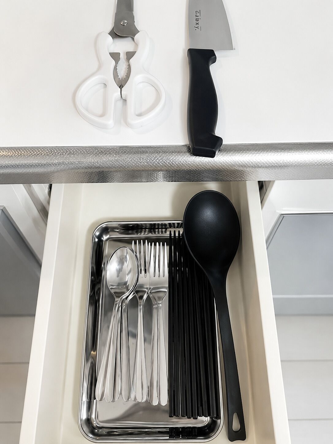 Un cajón de cocina con utensilios y un cuchillo.