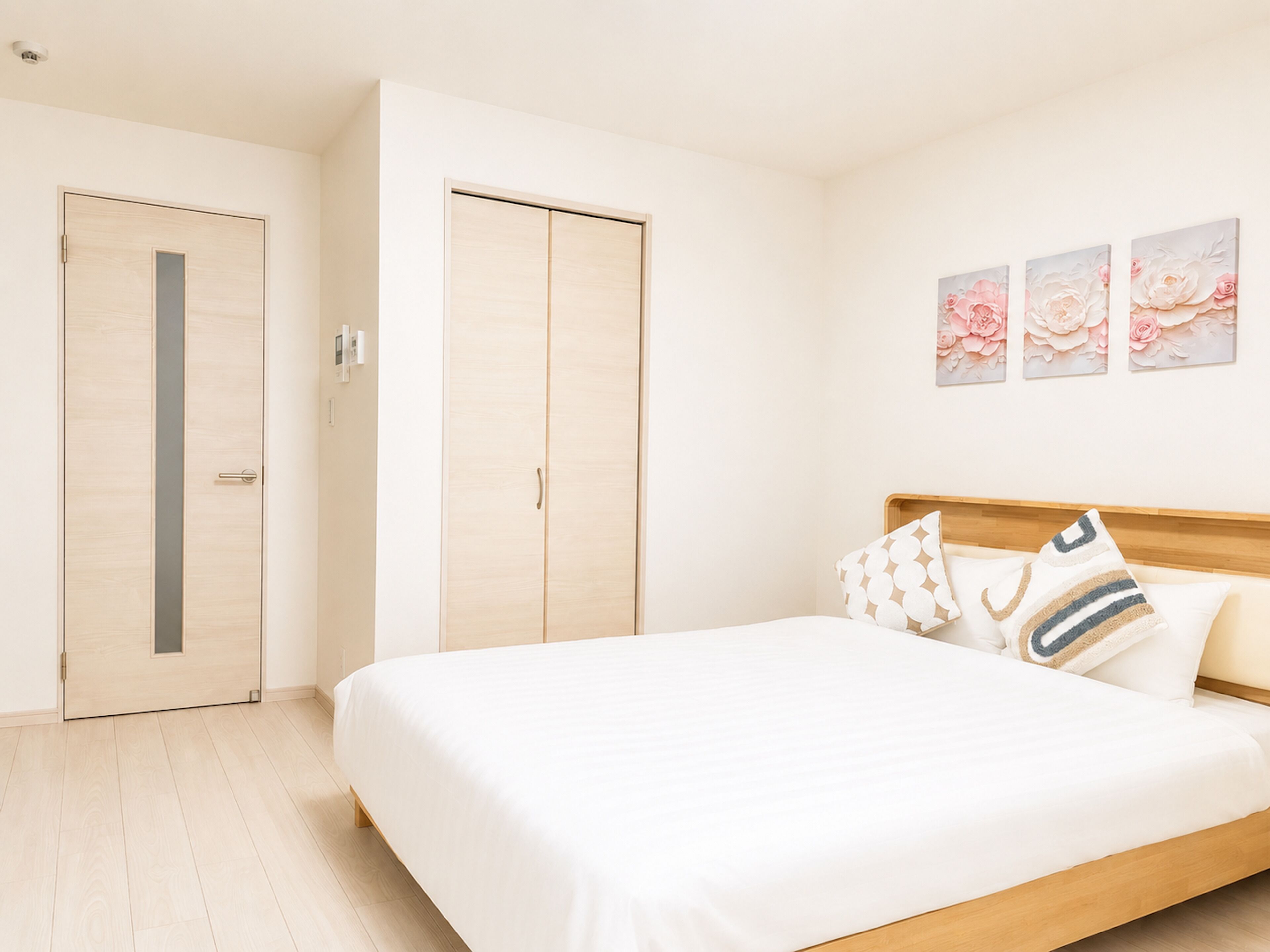Un dormitorio con una cama, un armario y tres cuadros florales.
