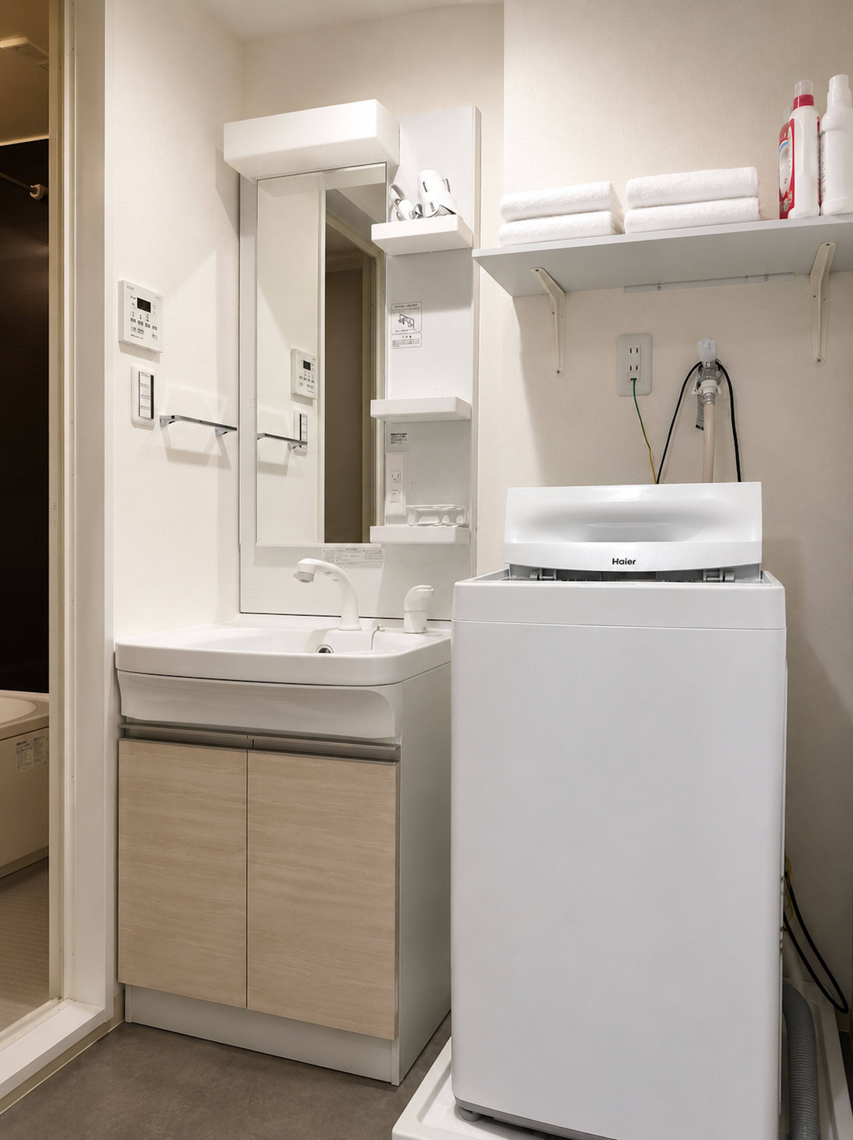 A modern bathroom with a white sink, mirror, and toilet, a built-in heater, and a towel rack.