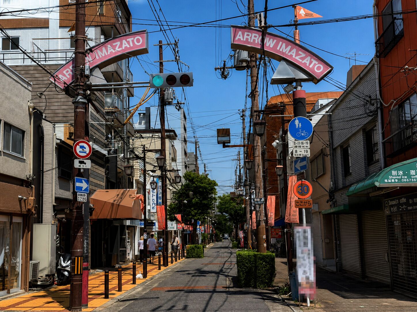 A street with multiple directional signs, a traffic light, and a pedestrian crossing sign.