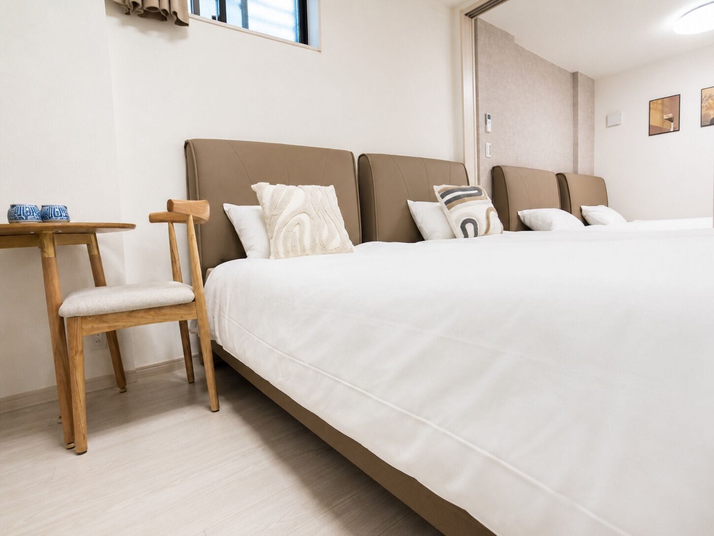 A hotel room with a large bed, a wooden chair, a small table, and a window.