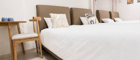 A hotel room with a large bed, a wooden chair, a small table, and a window.