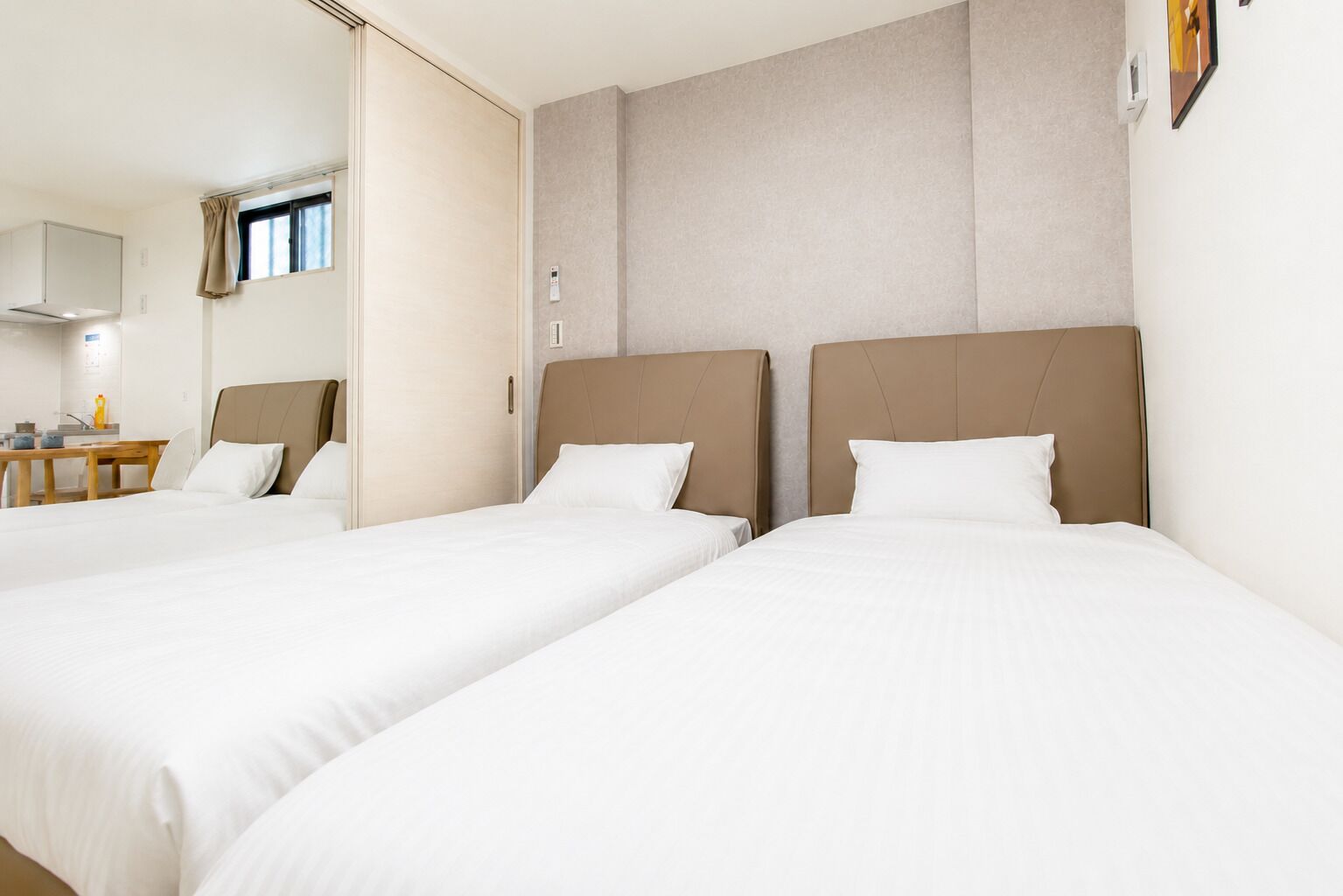 A hotel room with two beds, a desk, and a window.