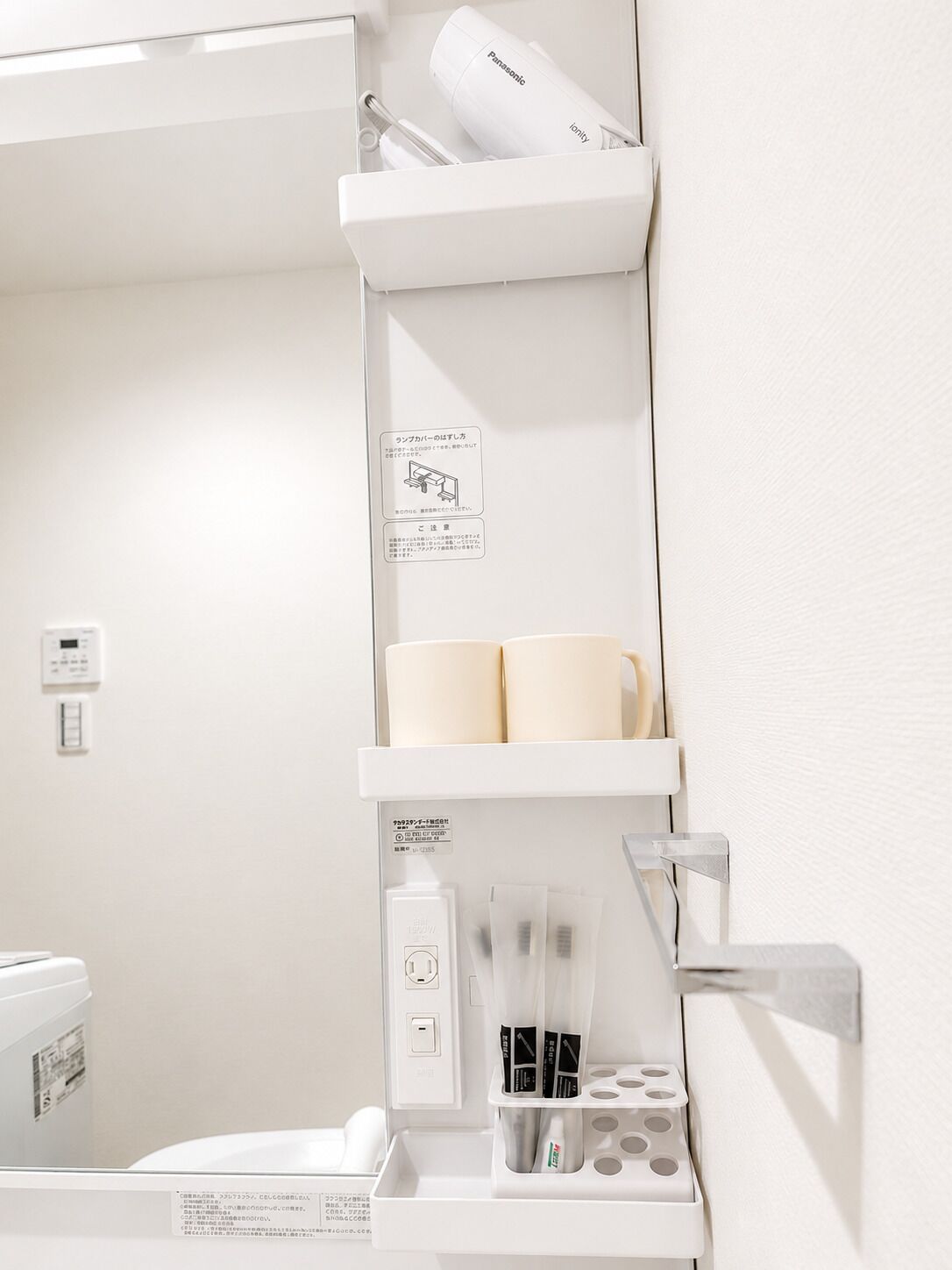 A bathroom with a white sink, a mirror, a towel rack, and a shelf with toiletries.