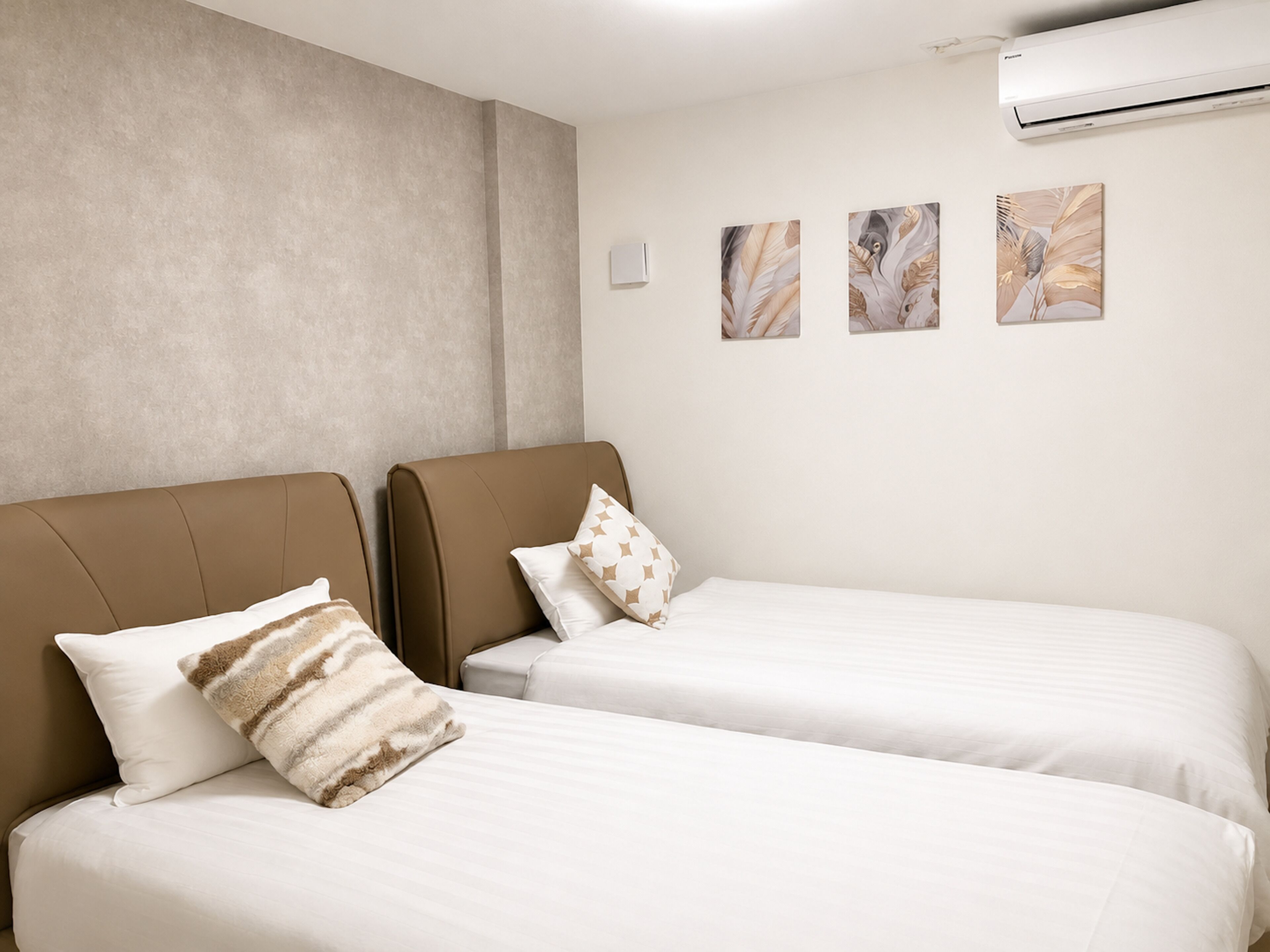 Quarto de hotel com duas camas, uma janela grande e um ar condicionado.