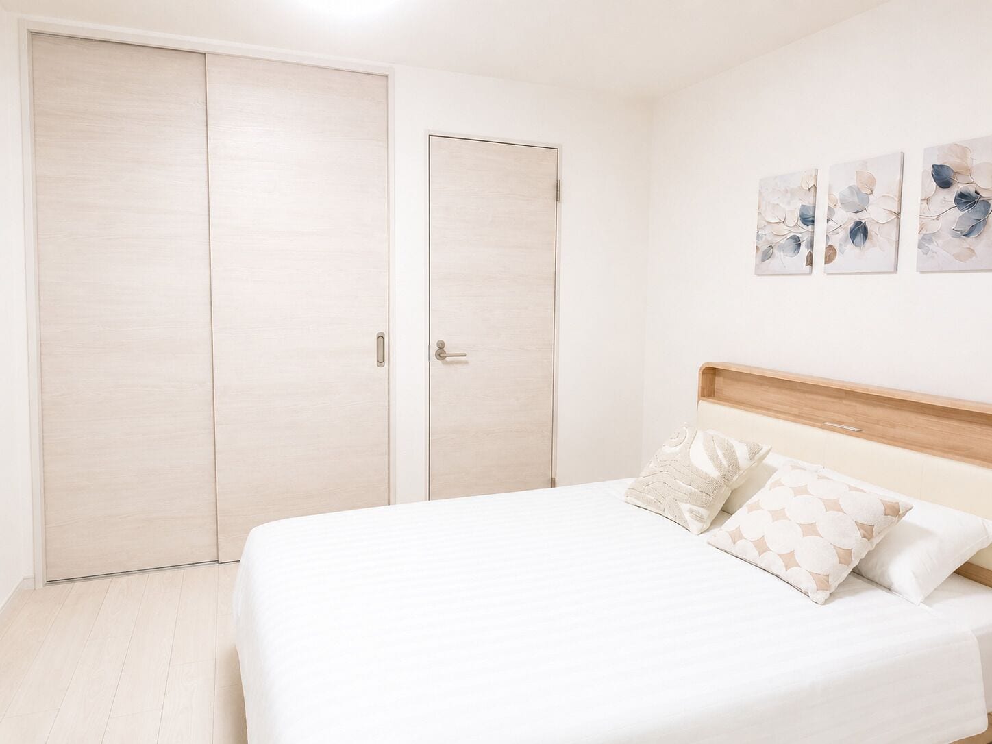 Een slaapkamer met een bed, twee deuren en drie kunstwerken aan de muur.