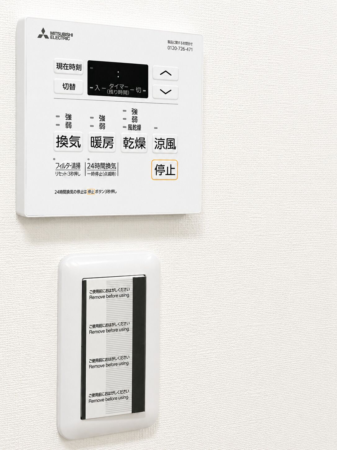 A Mitsubishi Electric thermostat with Japanese labels, a digital display, and a stop button.