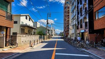 A street lined with residential buildings, a clear sky, and a bicycle parking area.