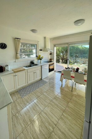 A modern kitchen with a large window, a dining area with a table, and a view of the outdoors. - Mediterranean villa with sea views, Lloret de Mar (Lloret de Mar)