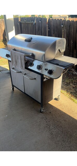 Ein tragbarer Grill aus Edelstahl mit Seitenbrenner, einem Stauraumschrank vorne und einem Handtuch am Griff.