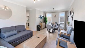 A modern living room with a sofa, coffee table, and dining area.
