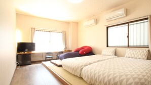 Een hotelkamer met een bed, een bureau met stoel, een televisie en een airconditioning.