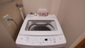 Een wasmachine met voorlader, voorzien van een bedieningspaneel, een stopcontact en een waterslang.
