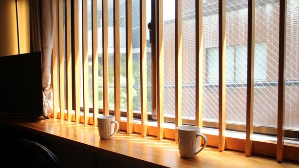 Een kamer met een houten vensterbank, twee witte keramische mokken en een televisie links.