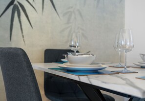 A dining table with a white bowl, a wine glass, and a fork on a blue placemat. - Traditional 2 bedroom ground floor apartment (Hamilton)