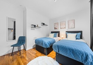 Ein Schlafzimmer mit zwei Betten, einem Stuhl und einem Spiegel.