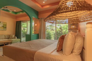Un dormitorio con cama, lámpara colgante, ventilador de techo y vista a zonas verdes al exterior.