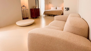 Un dormitorio amplio con una cama grande, una mesita de centro redonda y un diseño minimalista.