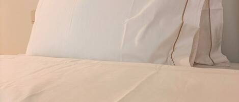 Una cama con ropa blanca y una almohada con el texto 'TERRA COTTA HOUSE'.
