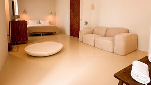 Una habitación de hotel moderna con cama, sofá, una mesa redonda y un mueble de madera.
