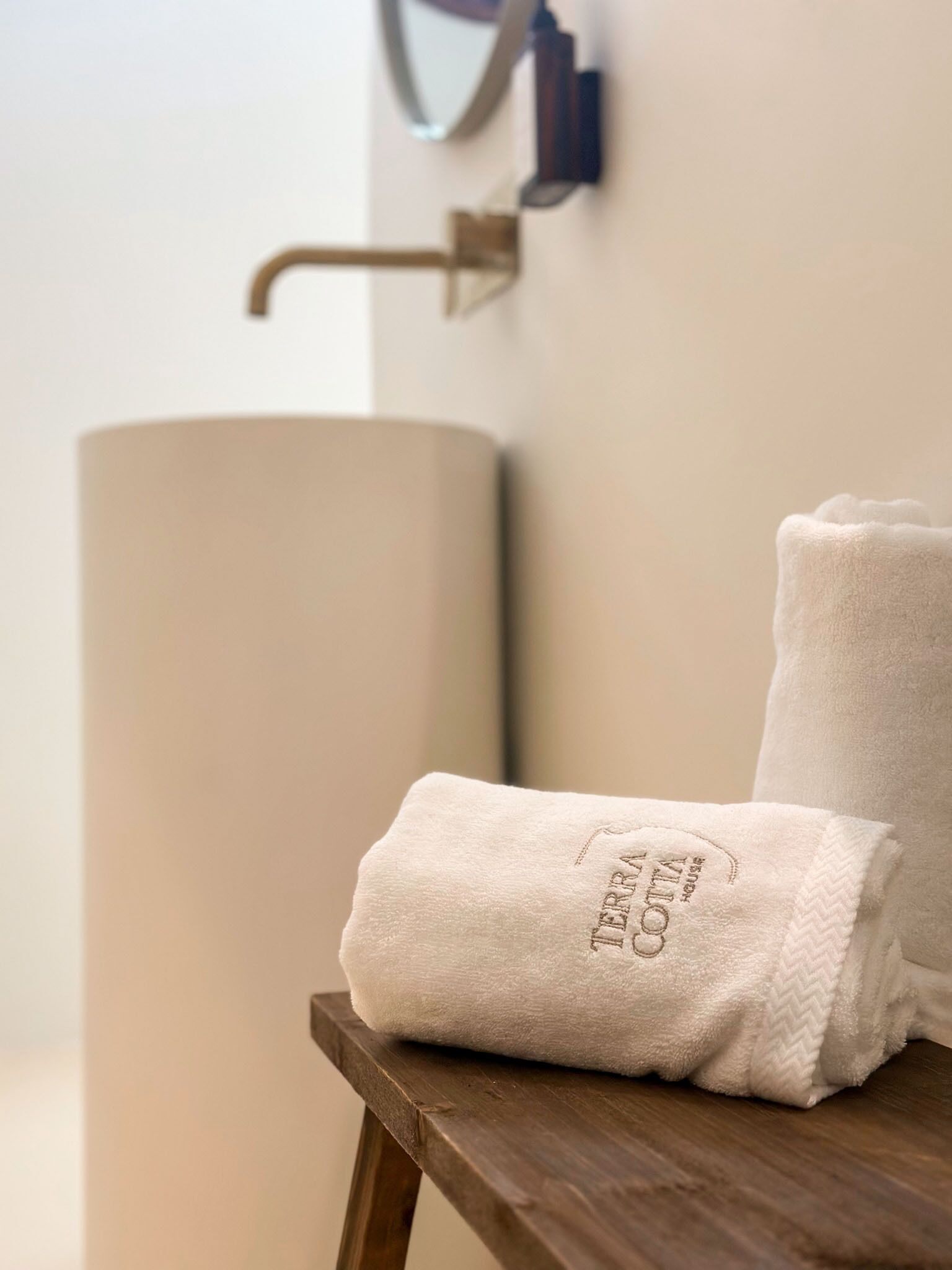 A bathroom with a large sink, a towel on a wooden surface, and a wall-mounted towel rack.
