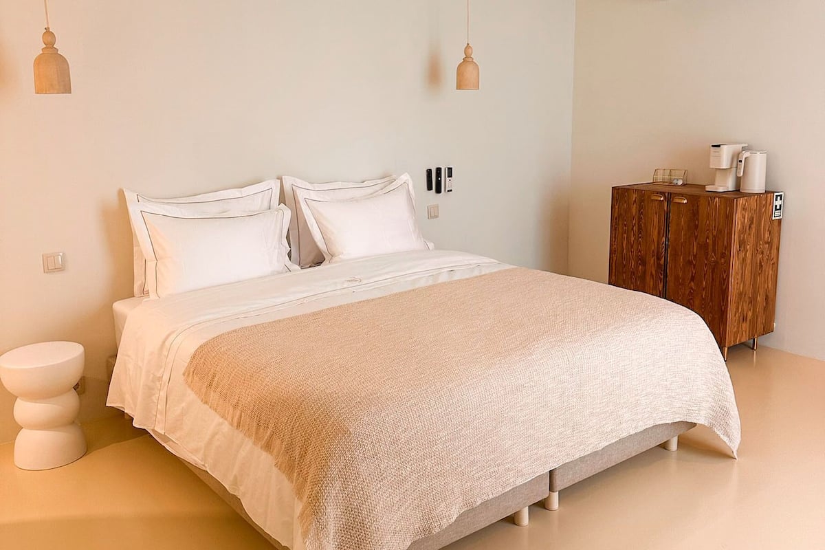 A bedroom with a bed, bedside tables, a wardrobe, and an air conditioning unit.
