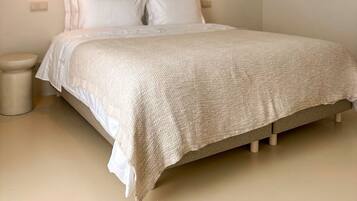 A bedroom with a bed, two pendant lights, an air conditioning unit, and a small bedside table.