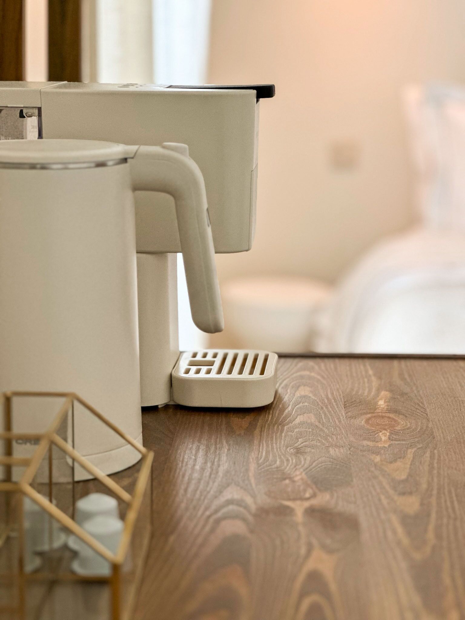 Une pièce moderne avec un plancher en bois, une machine à café blanche et une petite structure en bois.